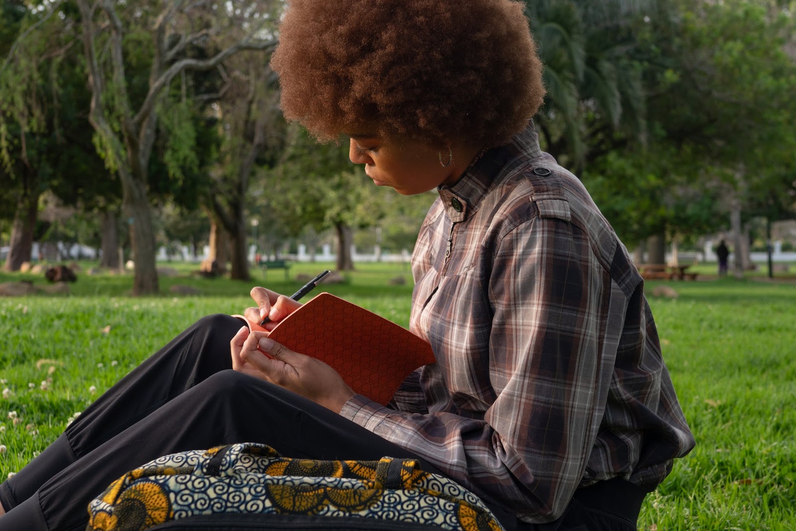 A girl sitting in a park reading a book.