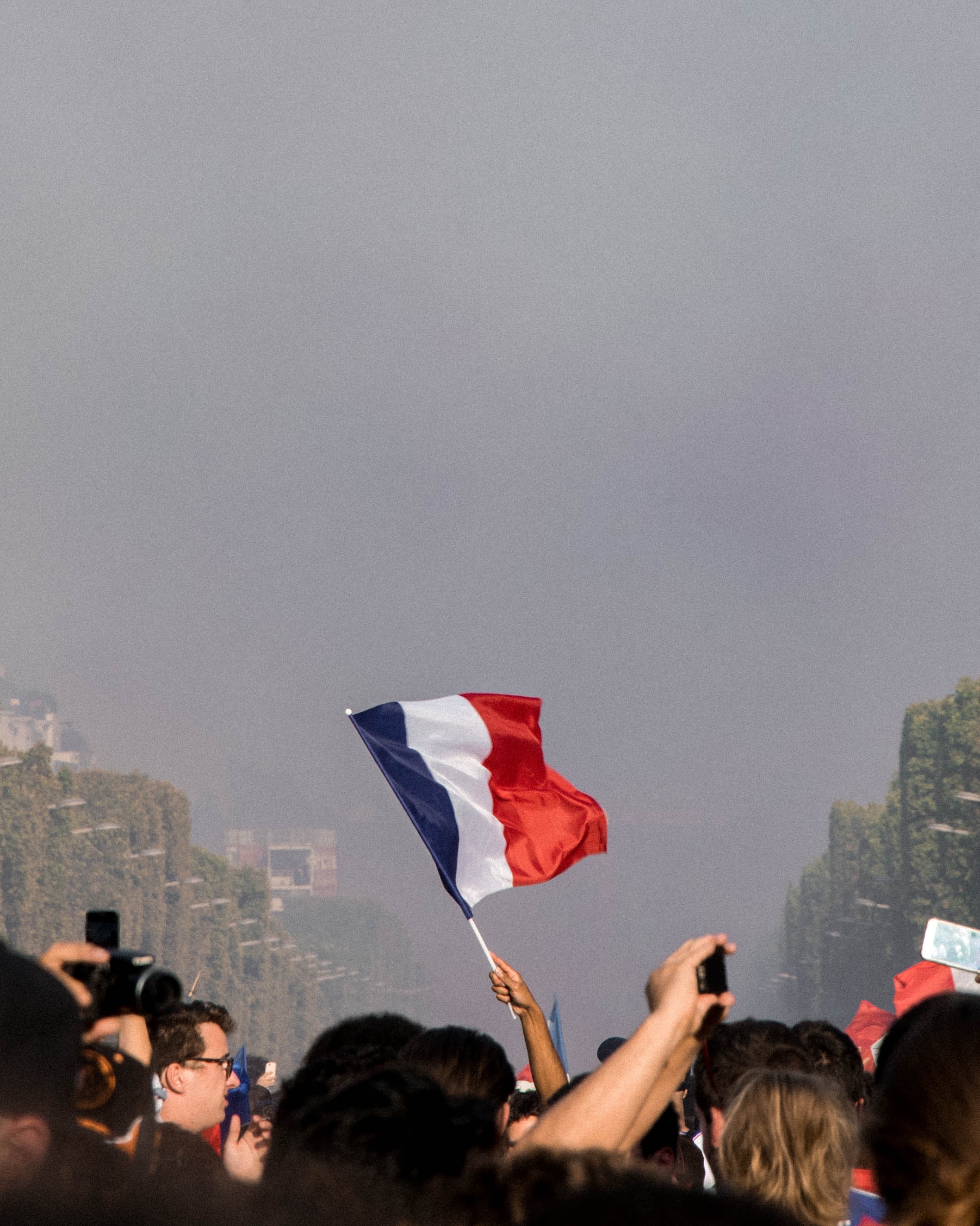A person waving a french flag in a crowd